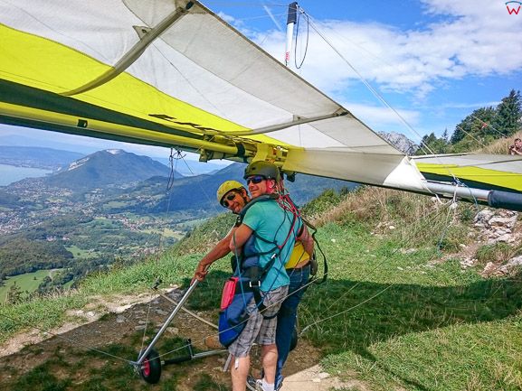 Montmin (Francja), 12.09.2015. Lotniarz w trakcie przygotowywania siÄ™ do lotu tandemowego na tle jeziora Jezioro Annecy